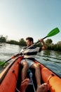 Active young man looking enthusiastic while kayaking in a lake, surrounded by peaceful nature on a summer afternoon