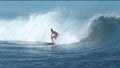 Active young man on surfboard rides a beautiful spraying tube wave to shore.