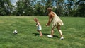 Active young mother playing football together with her little daughter on the grass field in the park on a summer day Royalty Free Stock Photo