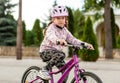 Active young school age girl, child riding a bike in a helmet, closeup. Kid rides a bicycle on a sunny day. Hands on handlebars Royalty Free Stock Photo