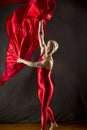 Young woman in red unitard swirling red fabric in studio. Royalty Free Stock Photo