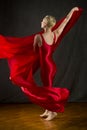 Young woman in red unitard swirling red fabric in studio. Royalty Free Stock Photo