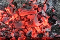 Actively smoldering embers of fire. The texture of the coal fire. Background of burning hot coals. Flicker of burning