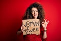 Activist with curly hair and piercing protesting holding poster with woman power message doing ok sign with fingers, excellent