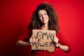 Activist with curly hair and piercing protesting holding poster with woman power message with a happy face standing and smiling