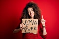 Activist with curly hair and piercing protesting holding poster with woman power message surprised with an idea or question