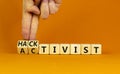 Activist or hacktivist symbol. Businessman turns wooden cubes and changes the word Activist to Hacktivist. Beautiful orange table