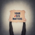 Activist hands holding up a cardboard banner with text message your vote matters, isolated on gray wall background. People legal Royalty Free Stock Photo