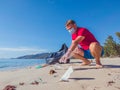 Activist volunteer Man in medical face mask pick up garbage that pollute beach sand near sea. Problem of spilled rubbish