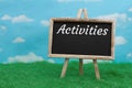 Activities message on standing chalkboard on grass with sky