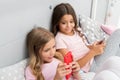 Activities for pajama party. Girls kids best friends or sisters wear pajama busy with smartphones. Children in pajama