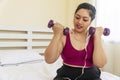 Activity exercise fit body diet or obesity concept. Positive overweight fat woman with measure tape on neck holding dumbbell