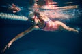 Activity. Young sportive woman, professional swimmer training in swimming pool indoor. Wearing cap and goggles Royalty Free Stock Photo