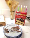 Acton, California / USA April 4, 2020: Candles on cake mix, Duncan Hines box, with blue plates and silver forks on white tile kitc