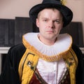 Actor dressed historical costume in interior of old theater.