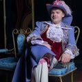 Actor dressed historical costume in interior of old theater.