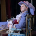 Actor dressed historical costume in interior of old theater.