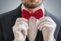 Actor or illusionist in white gloves is taking a red bowtie
