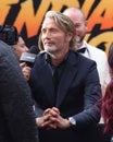 Actor Mads Mikkelsen dressed in a black suit giving an interview during a movie premiere event