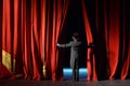 Actor in a tuxedo stage curtain opens