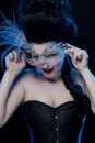 Actress brunette woman with high hair, a mask with feathers and corset in old style Royalty Free Stock Photo