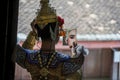 Actress khon wearing makeup and holding a mirror. Man wearing a traditional costume