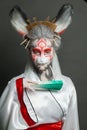 Actress woman with animal makeup, mask and stage asian costume posing on black background. Halloween, carnival