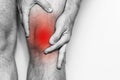 Acute pain in a knee joint, close-up. Monochrome image, on a white background. Pain area of red color
