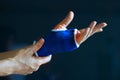 Acute pain in a senior hand wrist, safty in a bandage from stretch, colored in red on dark blue background