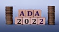 ADA 2022 - acronym on wooden cubes on a light background with coins Royalty Free Stock Photo