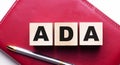 ADA Americans with Disabilities Act is made up of wooden cubes that stand on a burgundy notebook near the pen. Business concept Royalty Free Stock Photo