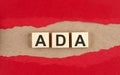 ADA word on wooden cubes on red torn paper Royalty Free Stock Photo