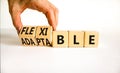 Adaptable or flexible symbol. Businessman turns wooden cubes and changes the word Adaptable to Flexible. Beautiful white table