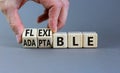 Adaptable or flexible symbol. Businessman turns wooden cubes and changes the word Adaptable to Flexible. Beautiful grey table grey Royalty Free Stock Photo