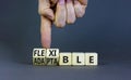 Adaptable or flexible symbol. Businessman turns wooden cubes and changes the word Adaptable to Flexible. Beautiful grey table grey Royalty Free Stock Photo