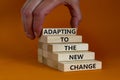 Adapting to the new change symbol. Wooden blocks with words Adapting to the new change on orange background, copy space.