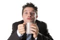 Addict businessman in suit and tie holding cup of coffee as maniac in caffeine addiction