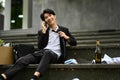 Addicted drunk asian man office worker talking on mobile phone sitting on stairs outside office building