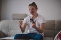 Addicted man on a game console sits on a gray sofa, reveling in a successful mission in a strategy game on television. The joy of Royalty Free Stock Photo