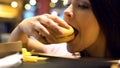 Addicted young woman eating harmful fat burger, lack of will power, overeating