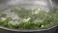 Adding butter to frying springtime fresh dill plants inside pan