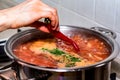 Adding chili pepper to borscht in saucepan close