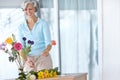 Adding a dash of color. a senior woman enjoying some flower arranging at home. Royalty Free Stock Photo