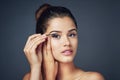 Adding that extra oomph with mascara. Studio shot of a beautiful young woman applying mascara while posing against a Royalty Free Stock Photo