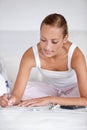 Adding a journal entry. A young woman calculating her financial budget while lying in bed. Royalty Free Stock Photo