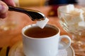 Adding lump of sugar with tweezers to tea in cup Royalty Free Stock Photo