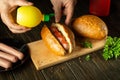 Adding mustard by the hands of the cook to the hot dog for taste. The concept of cooking fast food or street food Royalty Free Stock Photo