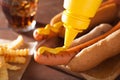 Adding mustard to grilled hot dog Royalty Free Stock Photo