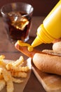 Adding mustard to grilled hot dog Royalty Free Stock Photo