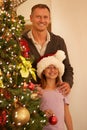 Adding the perfect finishing touch.... A father and his young daughter decorating the christmas tree at home. Royalty Free Stock Photo